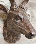 Bronze deer head sculpture on a textured wall