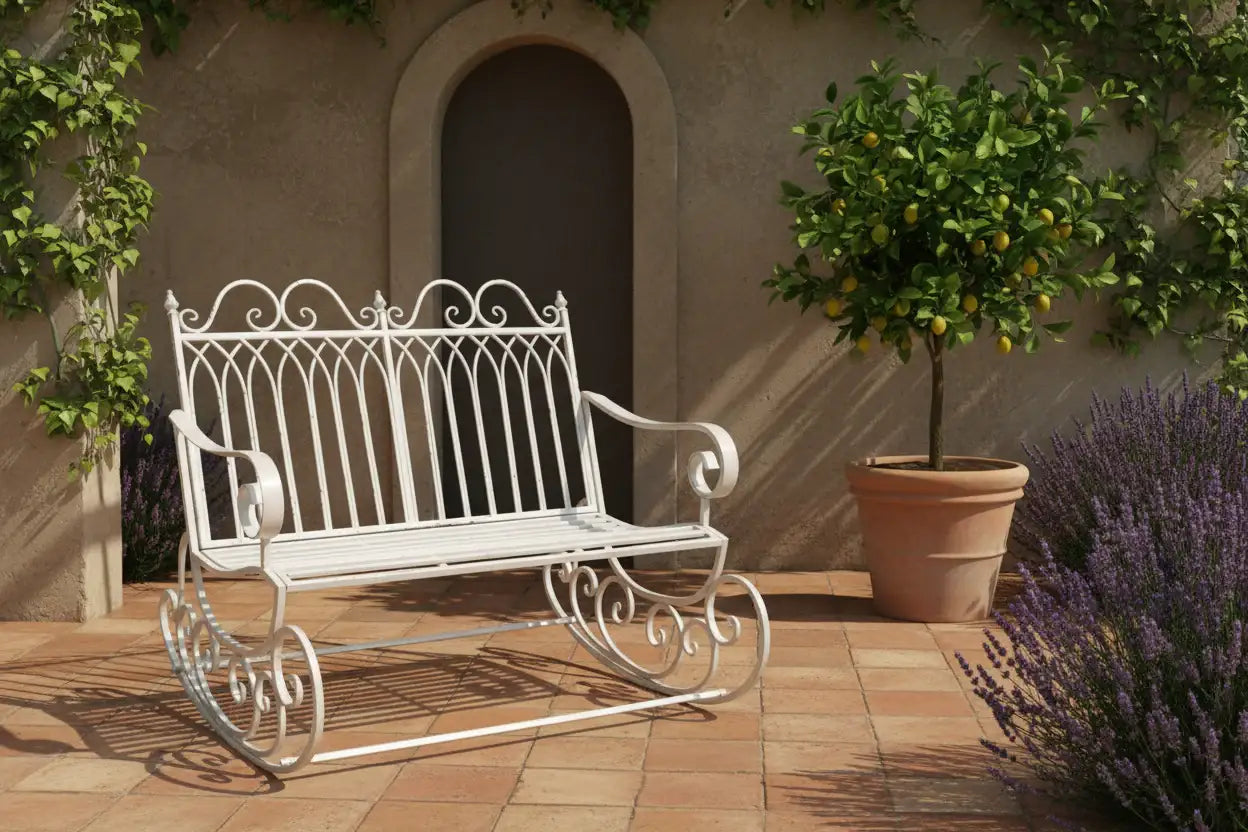 White metal bench on a patio with a potted tree and lavender plant.