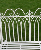 White metal bench with decorative backrest on a grassy background