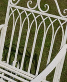 White metal garden chair with decorative backrest on a grassy background