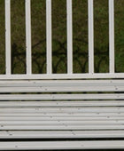 White metal bench with a grassy background