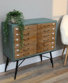 Wooden dresser with green top and black legs in a room setting.
