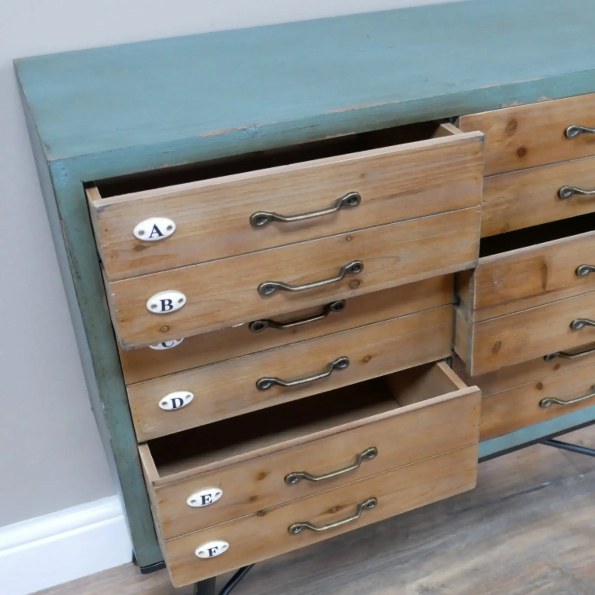 Wooden dresser with open drawers against a white wall
