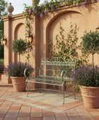 Wrought iron garden bench on grass with a fountain in the background