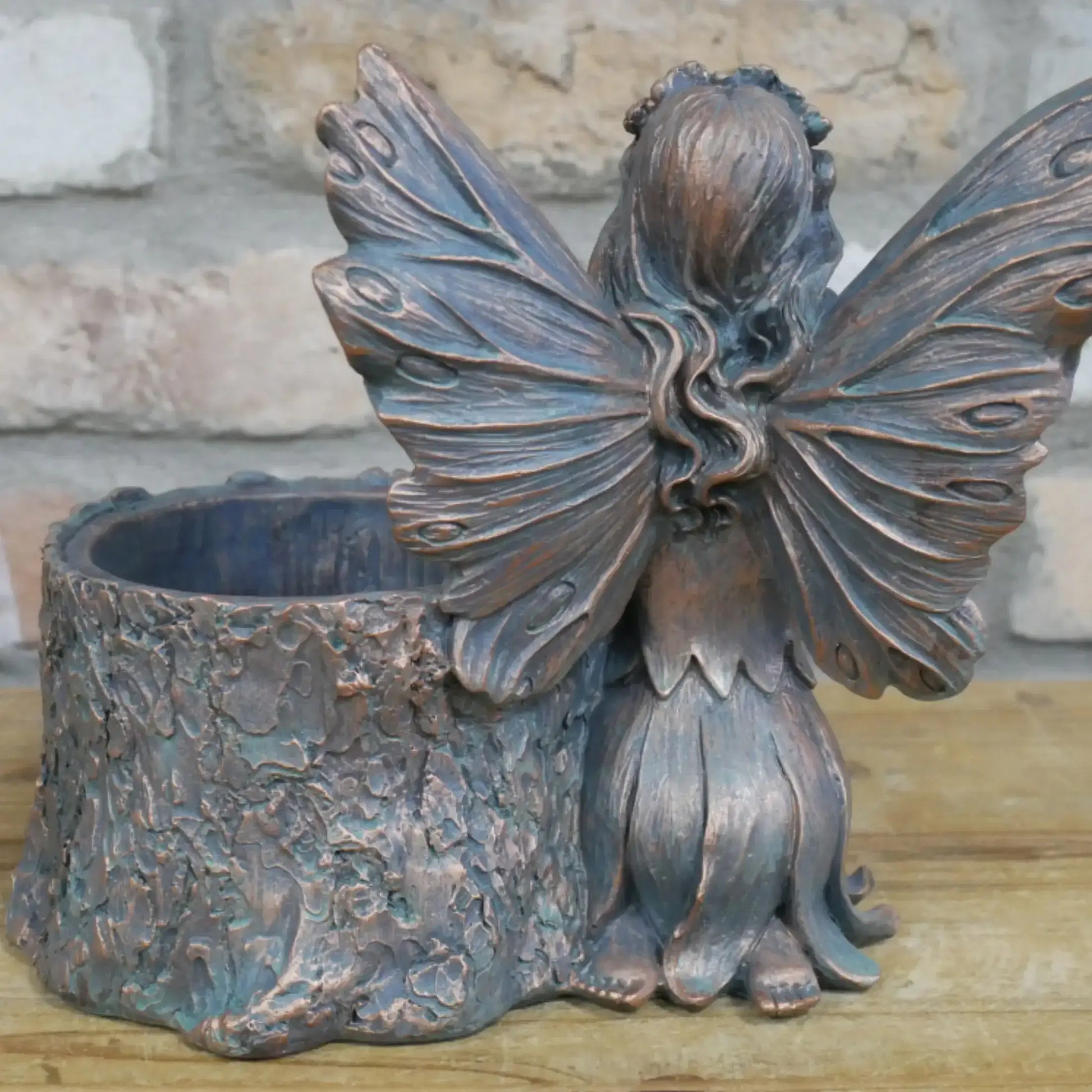 Bronze fairy figurine with butterfly wings on a stone surface