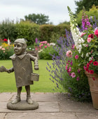 Statue of a child in a garden with flowers and plants