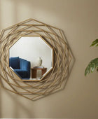 Decorative wall mirror with geometric design on a beige wall, next to a potted plant.