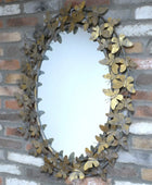Decorative mirror with leaf-like frame on a brick wall