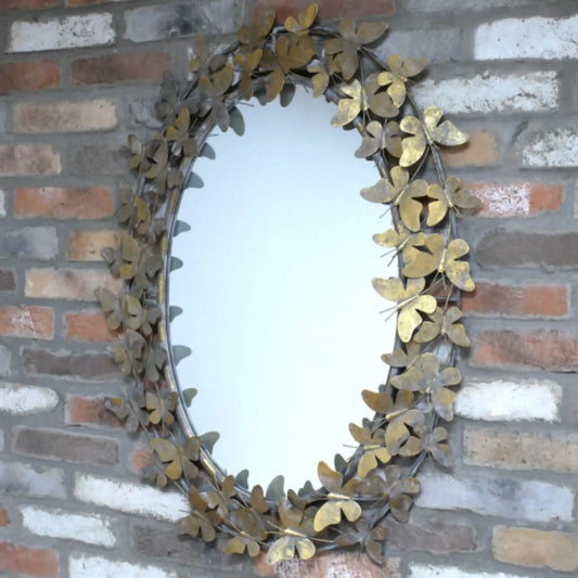 Decorative mirror with leaf-like frame on a brick wall