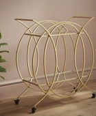 Gold circular magazine rack on wheels next to a plant against a beige wall.