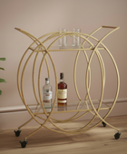 Gold circular bar cart with bottles and glasses on a wooden floor.