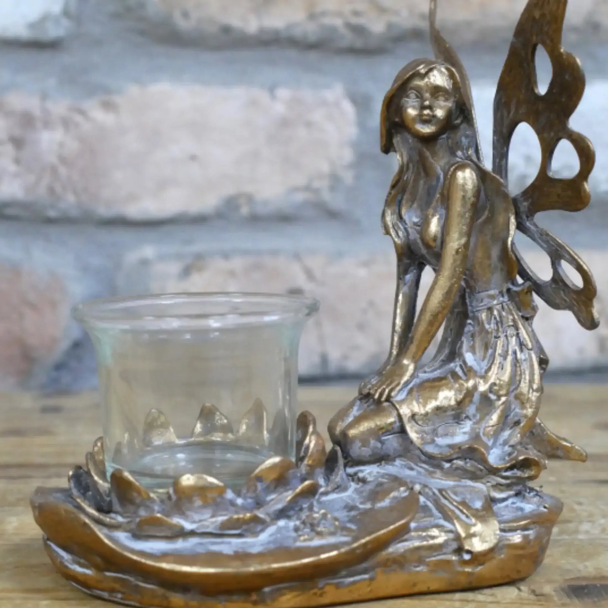 Bronze fairy figurine with a glass candle holder on a wooden surface
