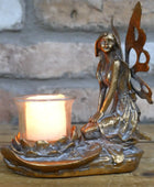 Bronze fairy figurine with a candle holder against a stone wall background