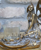 Bronze fairy figurine with a glass candle holder on a wooden surface