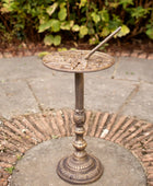 Decorative bronze sundial on a stone pedestal outdoors.