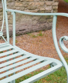 Light blue metal chair in a garden setting with a stone wall in the background