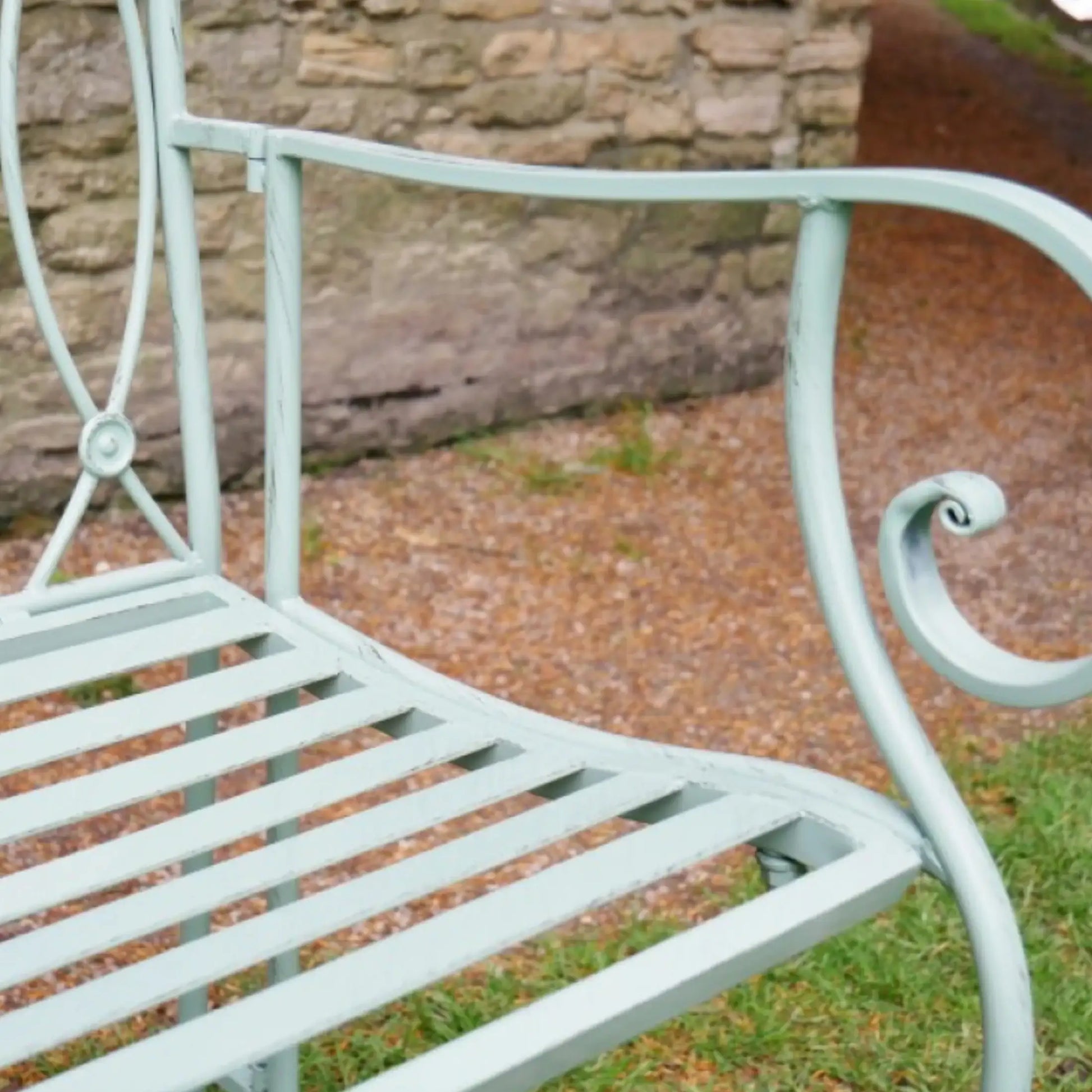 Light blue metal chair in a garden setting with a stone wall in the background