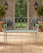 Decorative metal bench on a patio with potted plants and a garden gate in the background.
