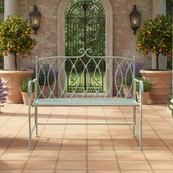 Decorative metal bench on a patio with potted plants and a garden gate in the background.