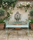 Vintage-style metal bench in a garden setting with flowers and plants.