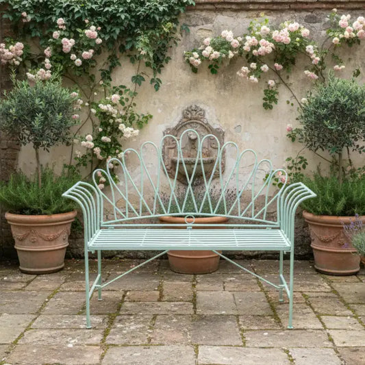 Vintage-style metal bench in a garden setting with flowers and plants.