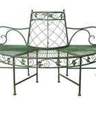 Green metal bench with decorative patterns on a wooden floor.