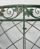 Close-up of a green metal gate with decorative leaves and swirls on a white background