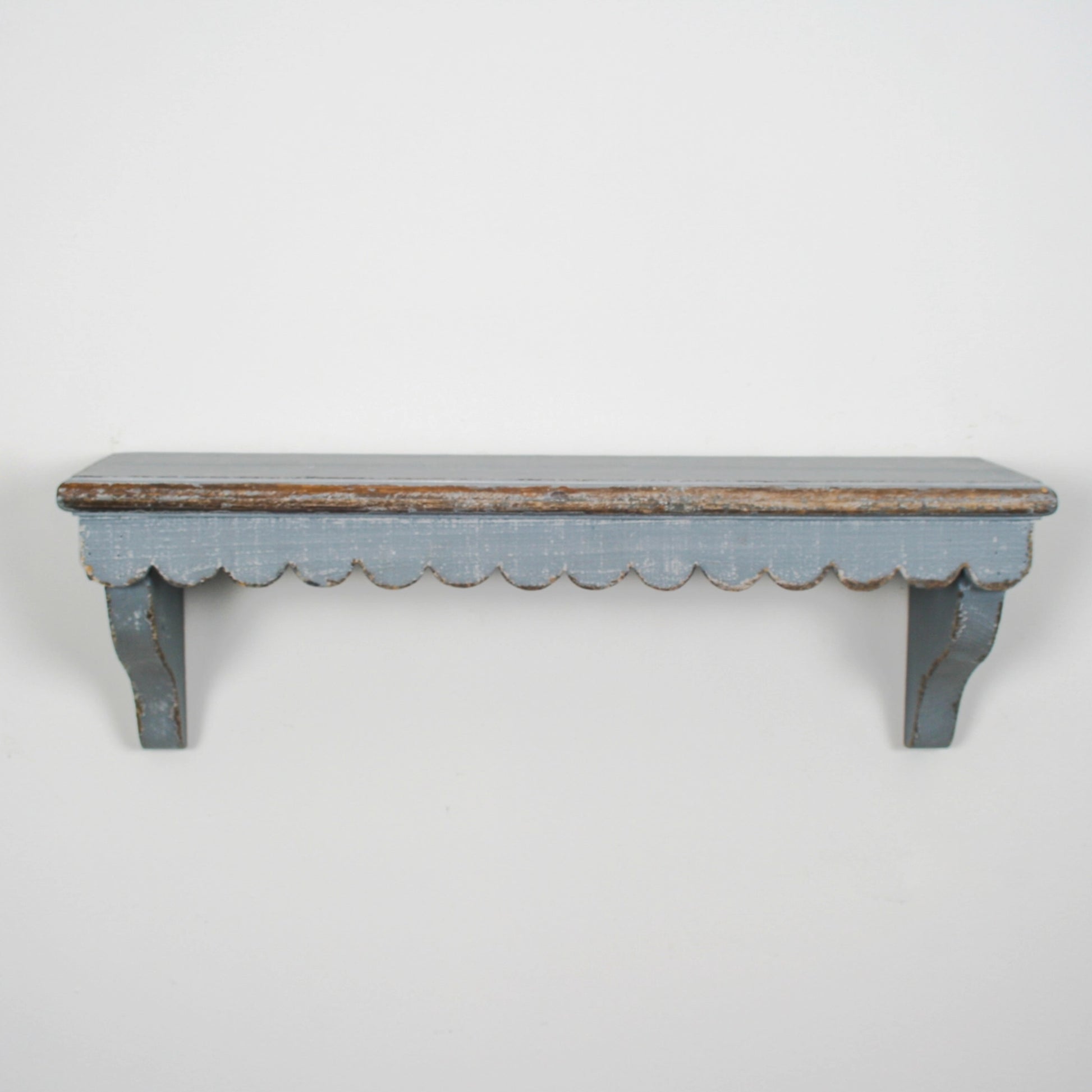 Worn wooden shelf with scalloped edge on a white background