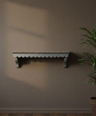 Wooden shelf on a plain wall with a plant to the right