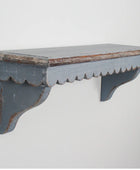 Worn wooden shelf with scalloped edge on a light gray background