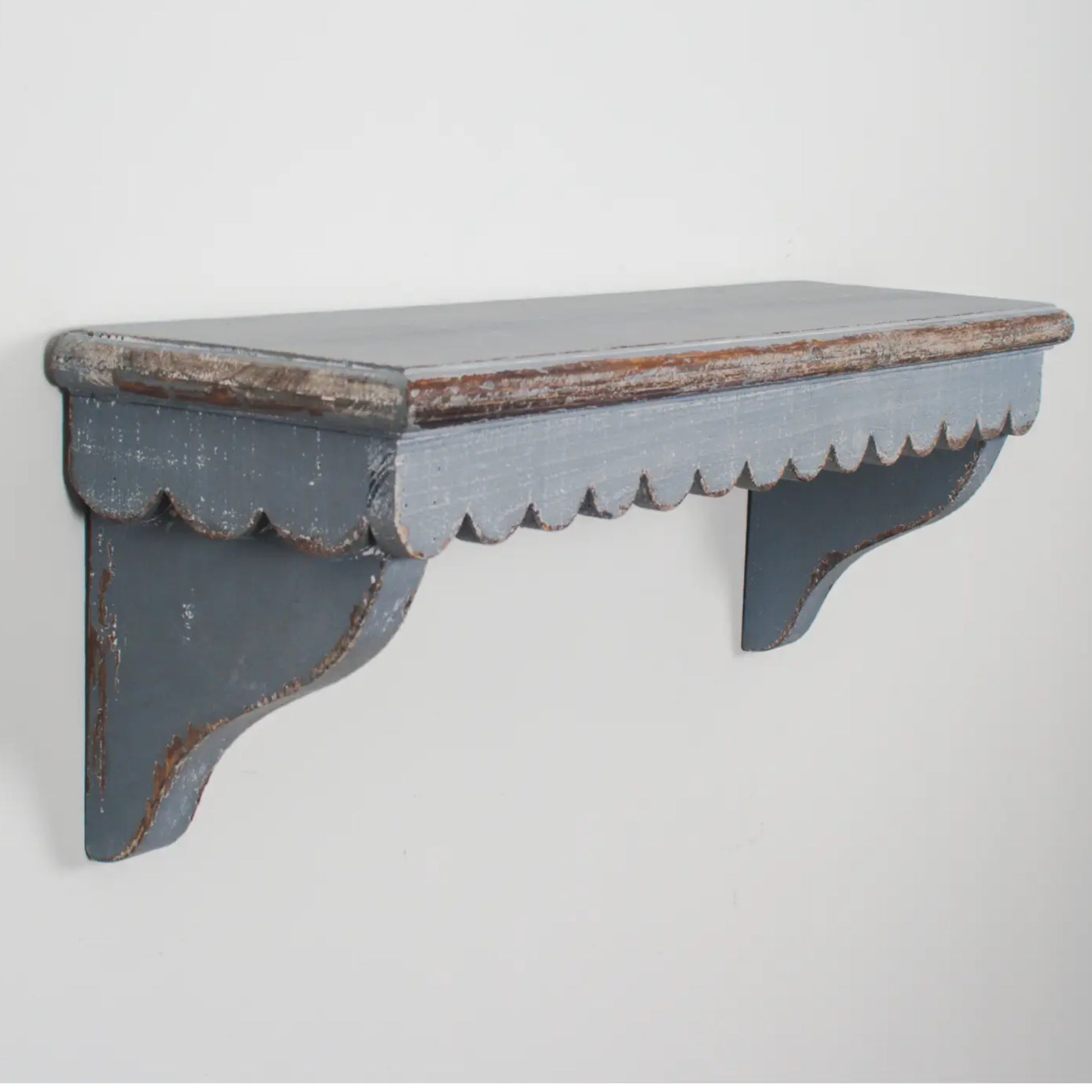 Worn wooden shelf with scalloped edge on a light gray background