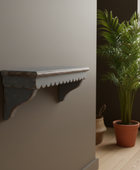 Decorative shelf on a wall next to a potted plant in a room.