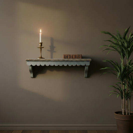 Wall shelf with candle and books against a plain wall, next to a potted plant.