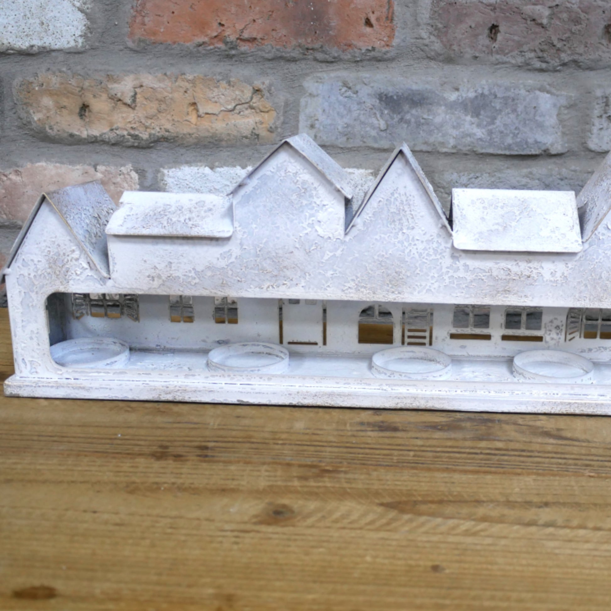 Model of a house on a wooden surface with a brick wall background
