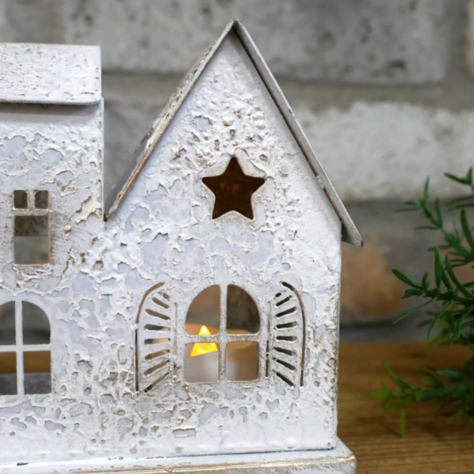 Decorative house-shaped lantern with a candle inside, featuring cut-out windows and a star design.