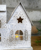 Decorative house-shaped lantern with a candle inside, featuring cut-out windows and a star design.