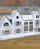 Decorative white house model on a wooden surface with a brick wall background