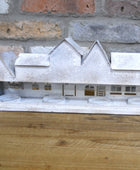 Model of a house on a wooden surface with a brick wall background