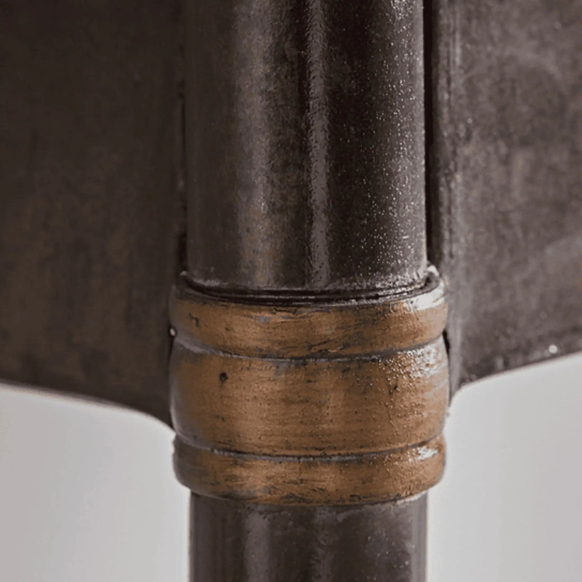 Close-up of a metal pipe with a bronze fitting on a white background