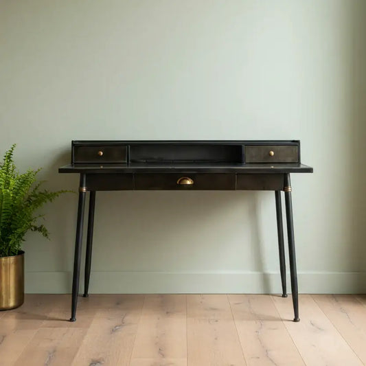 Black desk with gold accents against a light green wall