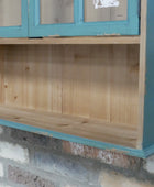 Wooden shelf with blue trim against a brick wall