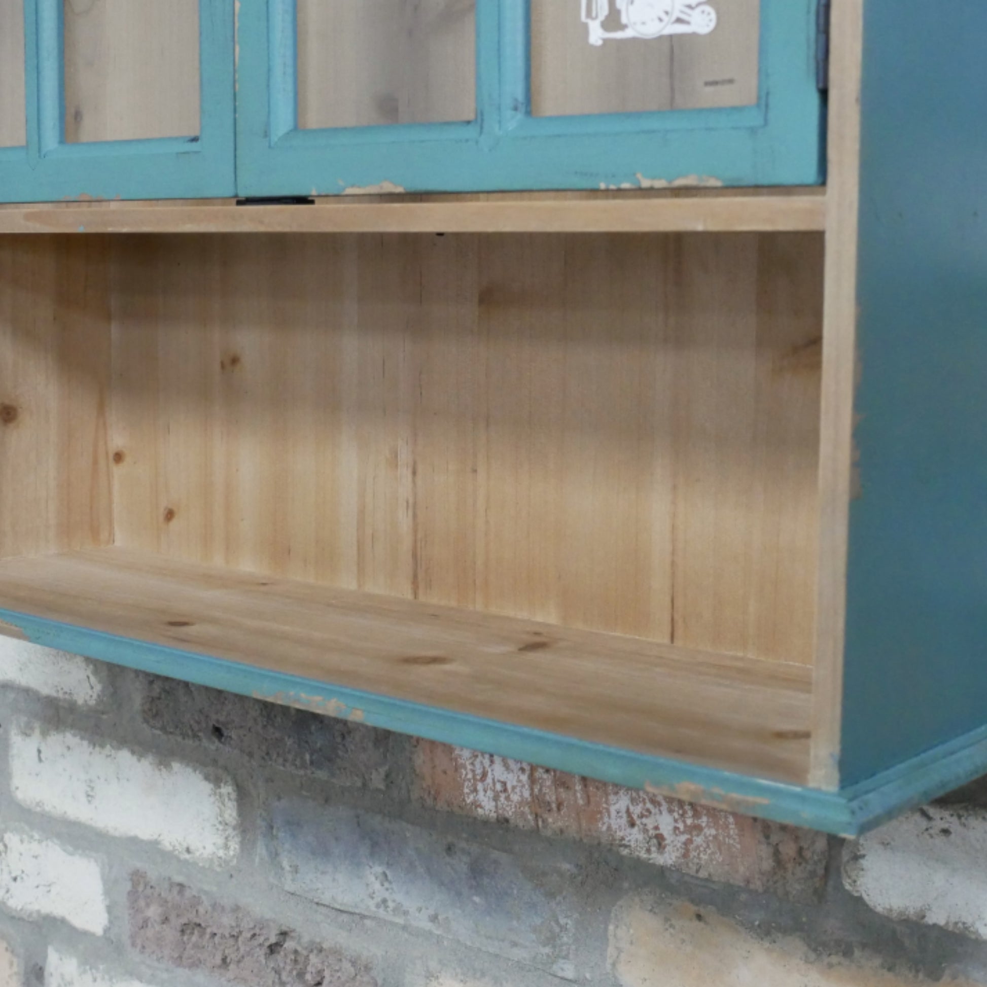 Wooden shelf with blue trim against a brick wall