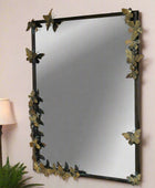 Decorative mirror with butterfly design on a wall next to a lamp and plant.