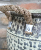 Decorative metal bucket with rope handle and decorative elements on a blurred background