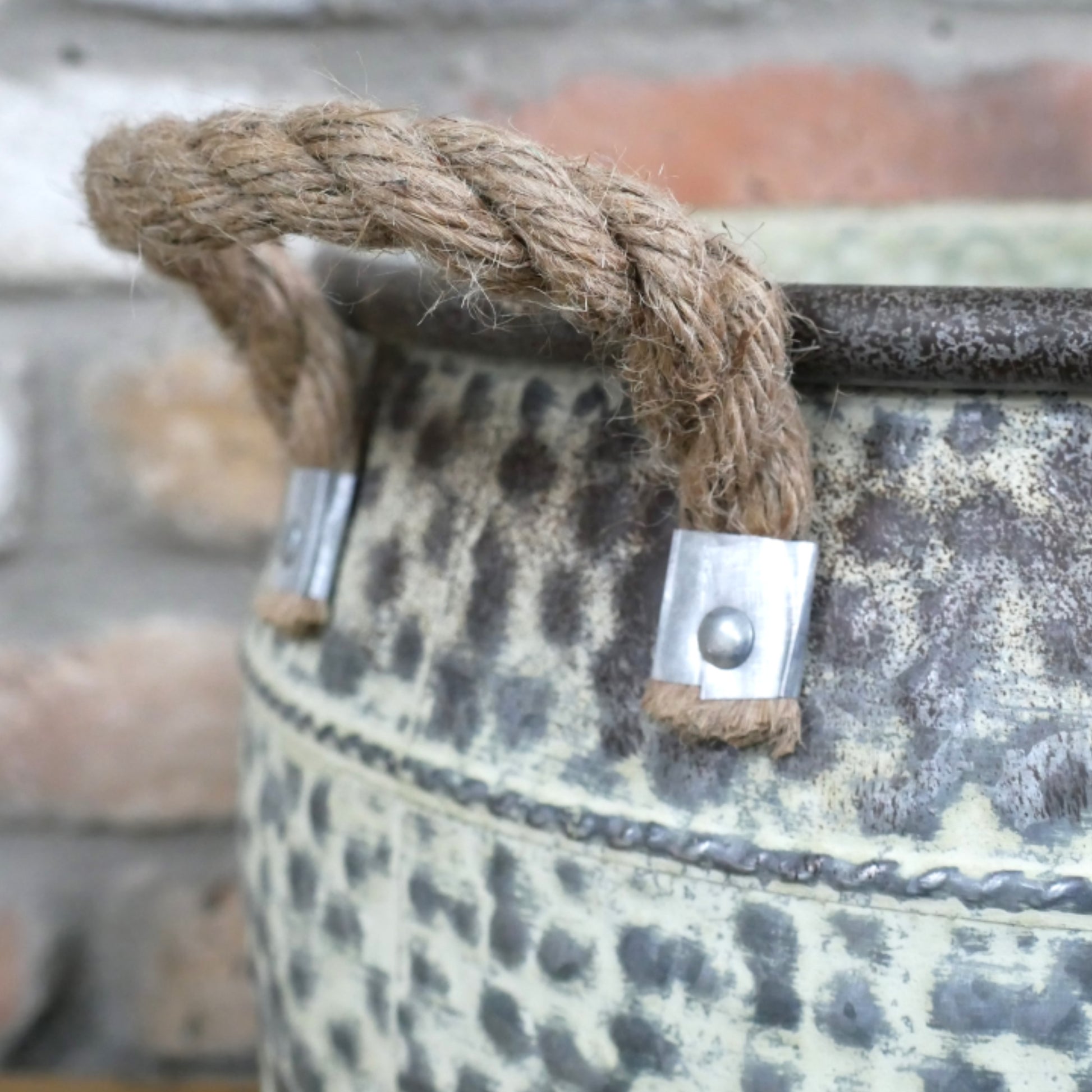 Decorative metal bucket with rope handle and decorative elements on a blurred background