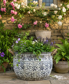 Decorative garden with potted plants and flowers against a stone wall.