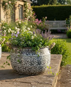 Decorative garden with potted plants and flowers against a stone wall.