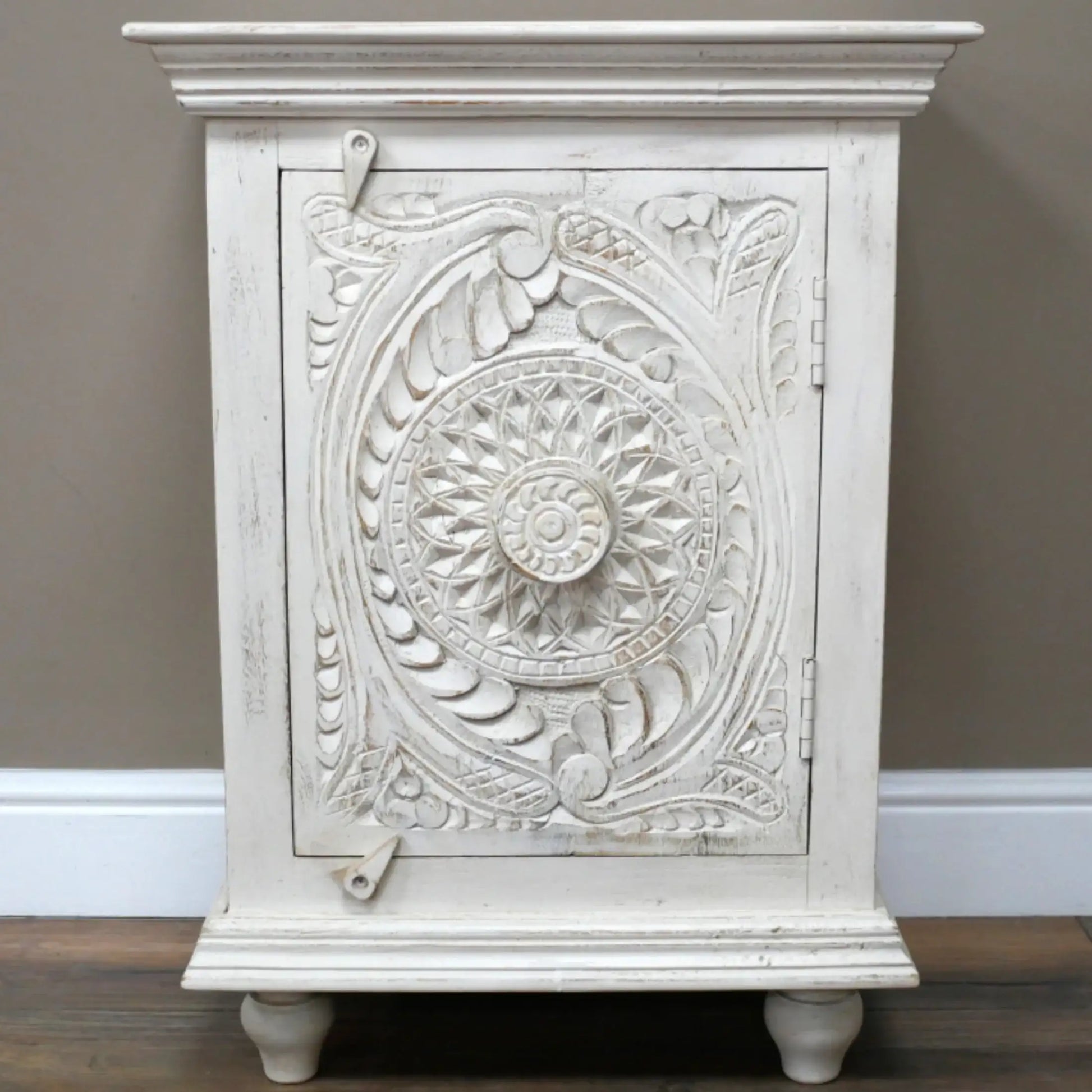 Decorative white cabinet with intricate carvings on a plain background