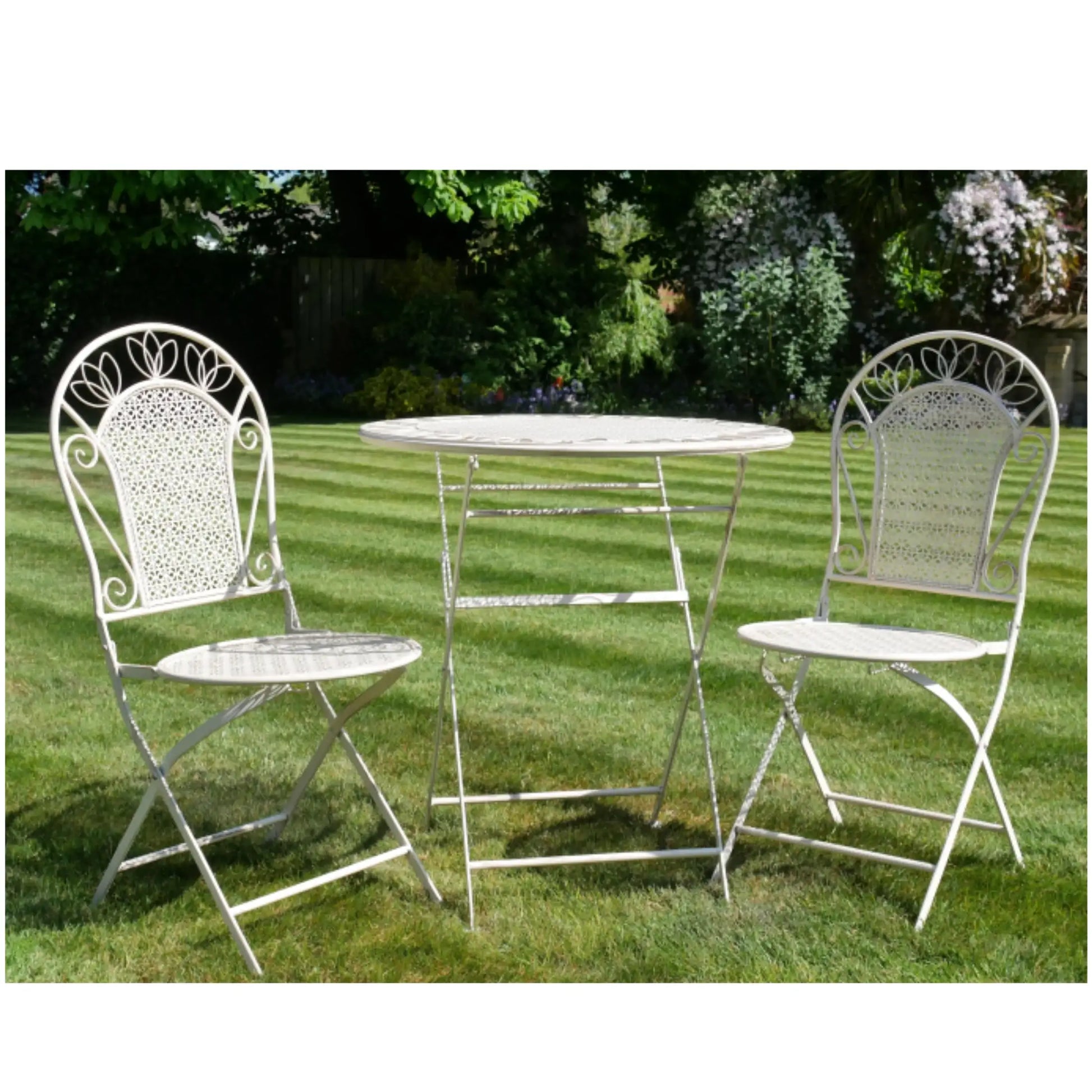 White metal garden table and chairs on grass with a garden background