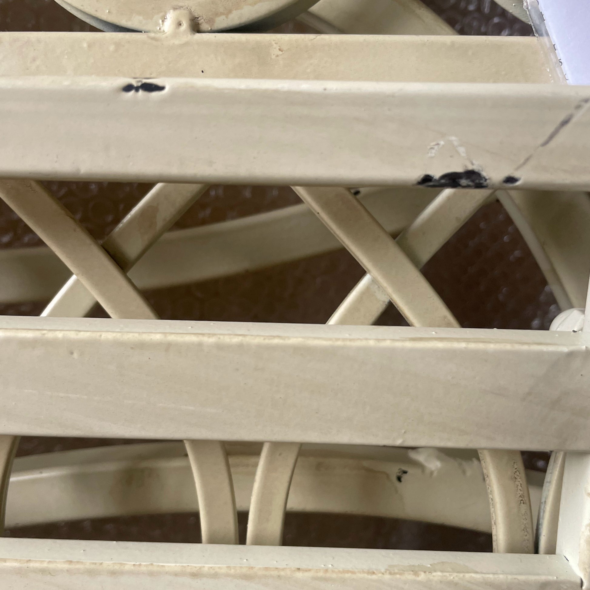 Close-up of a white metal lattice structure with visible wear and rust.